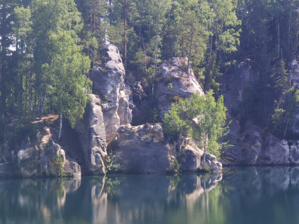 Adersbacher Felsenstadt See: Am Rand ragen die Felsen aus dem Wasser. Im See leben Fische.